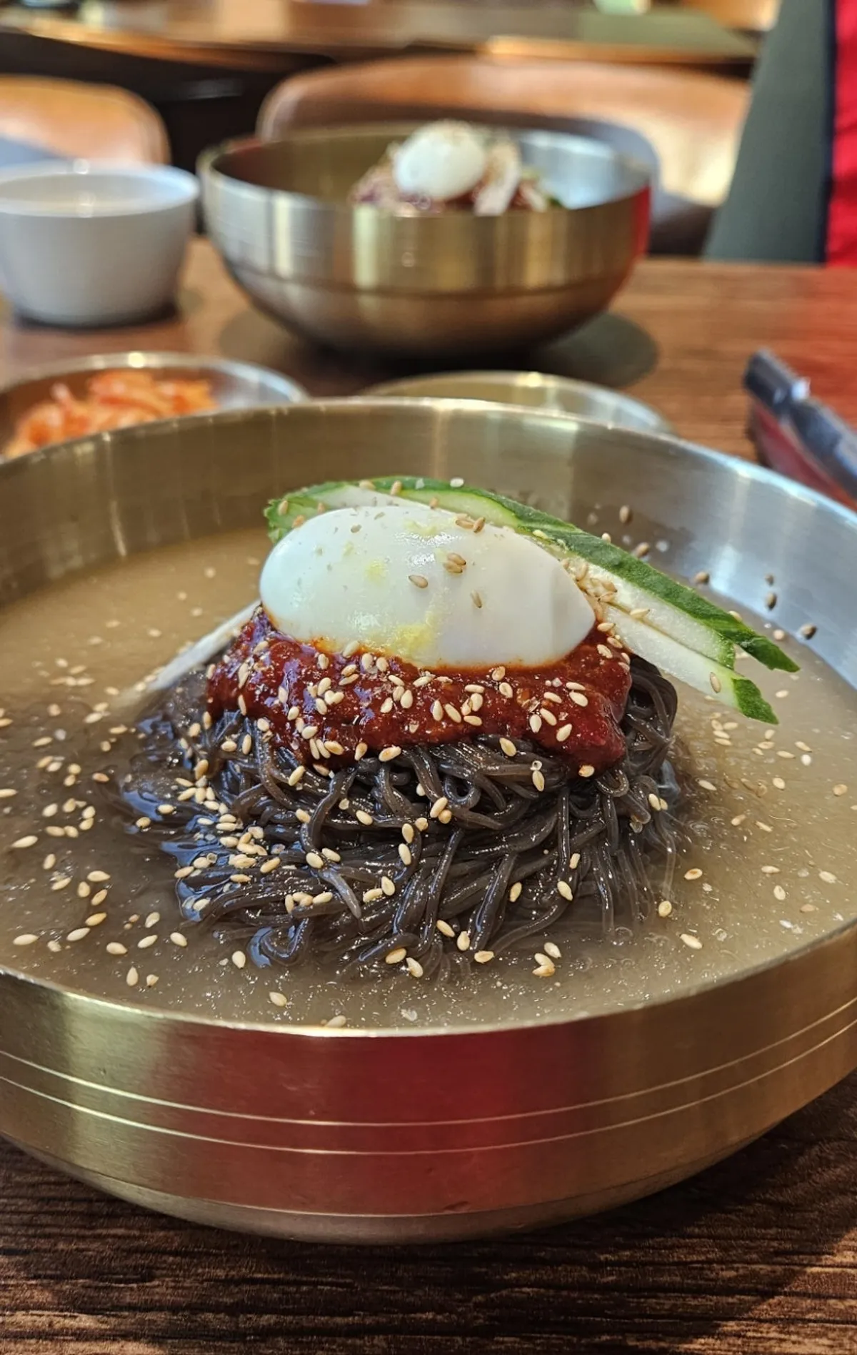 Table spread of mul naengmyeon, bibim naengmyeon, and octopus mandu