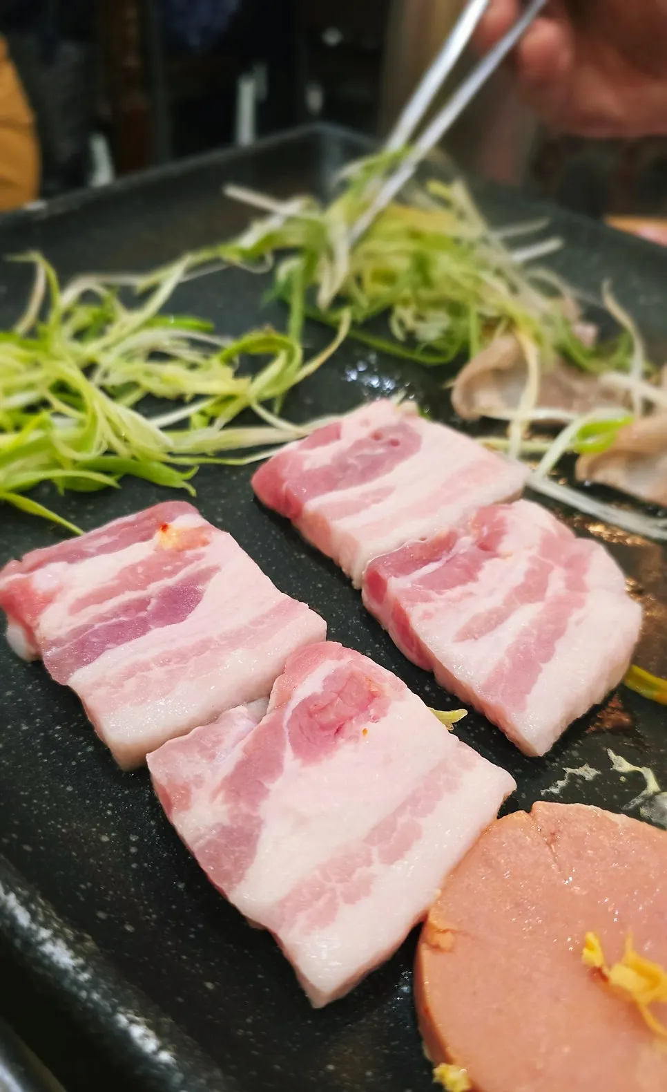 Thick pork belly grilling to golden brown on the pan