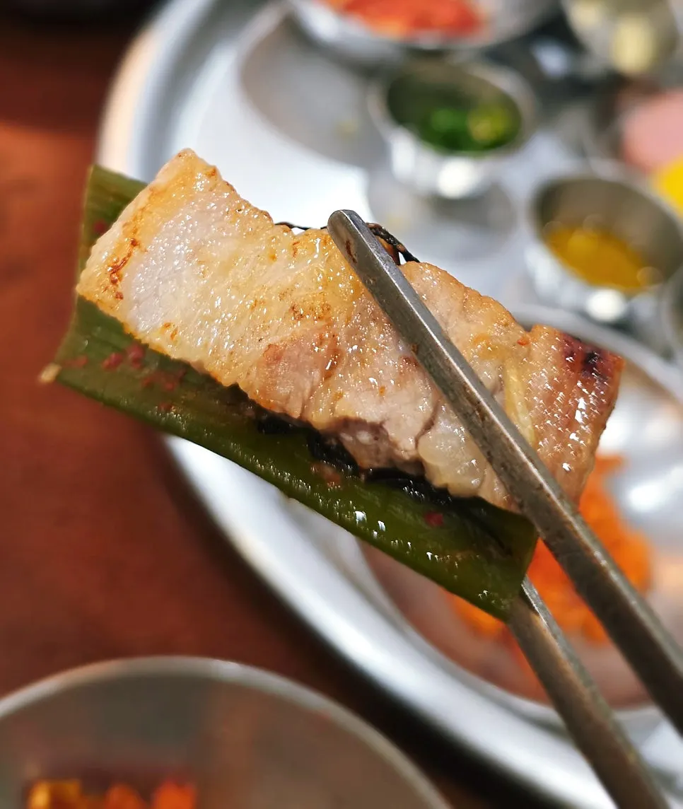 A bite of pork belly paired with green onion kimchi