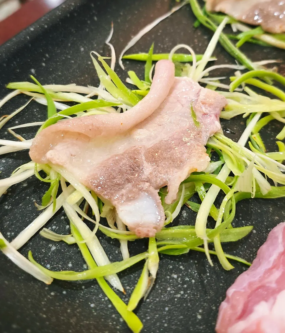 Meat and side dishes grilling together on the pan