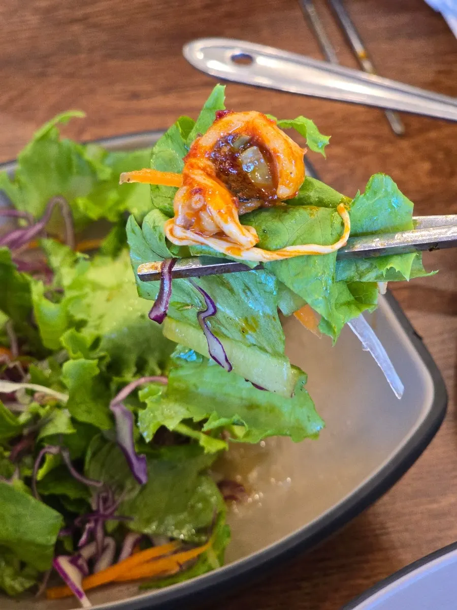 A bite of spicy octopus lifted up with melted cheese
