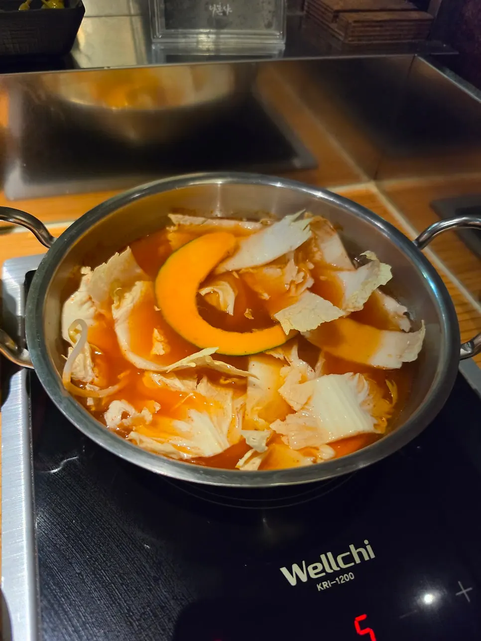 Bubbling spicy broth with a plate of thinly sliced meat