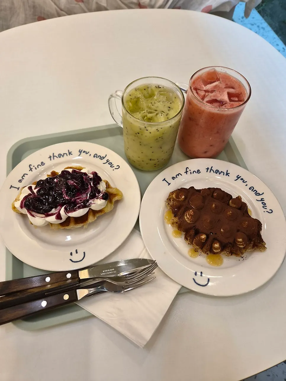 Two glasses of fresh fruit juice and two croffle plates on the table