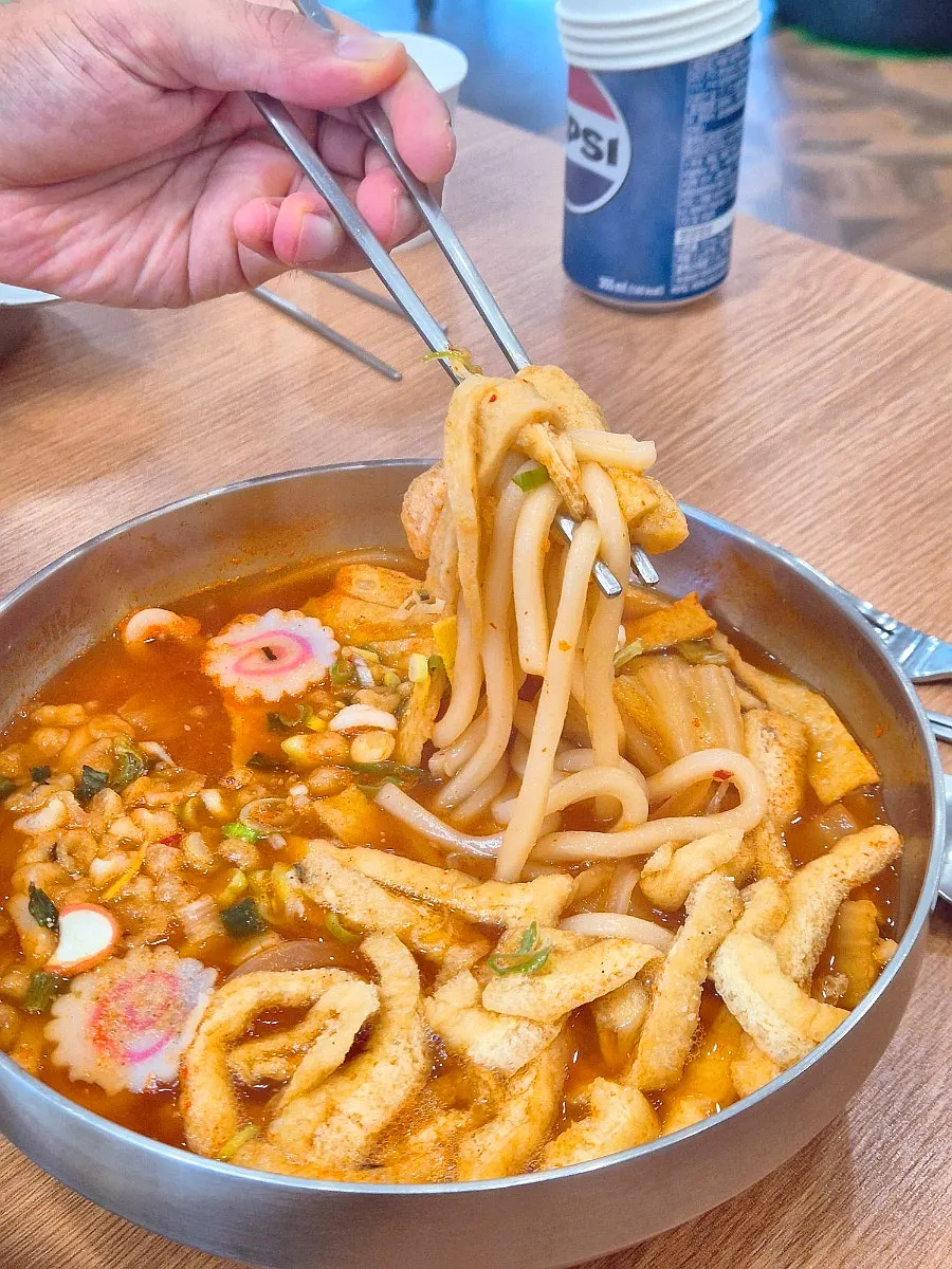 Kimchi udon noodles lifted up with chopsticks