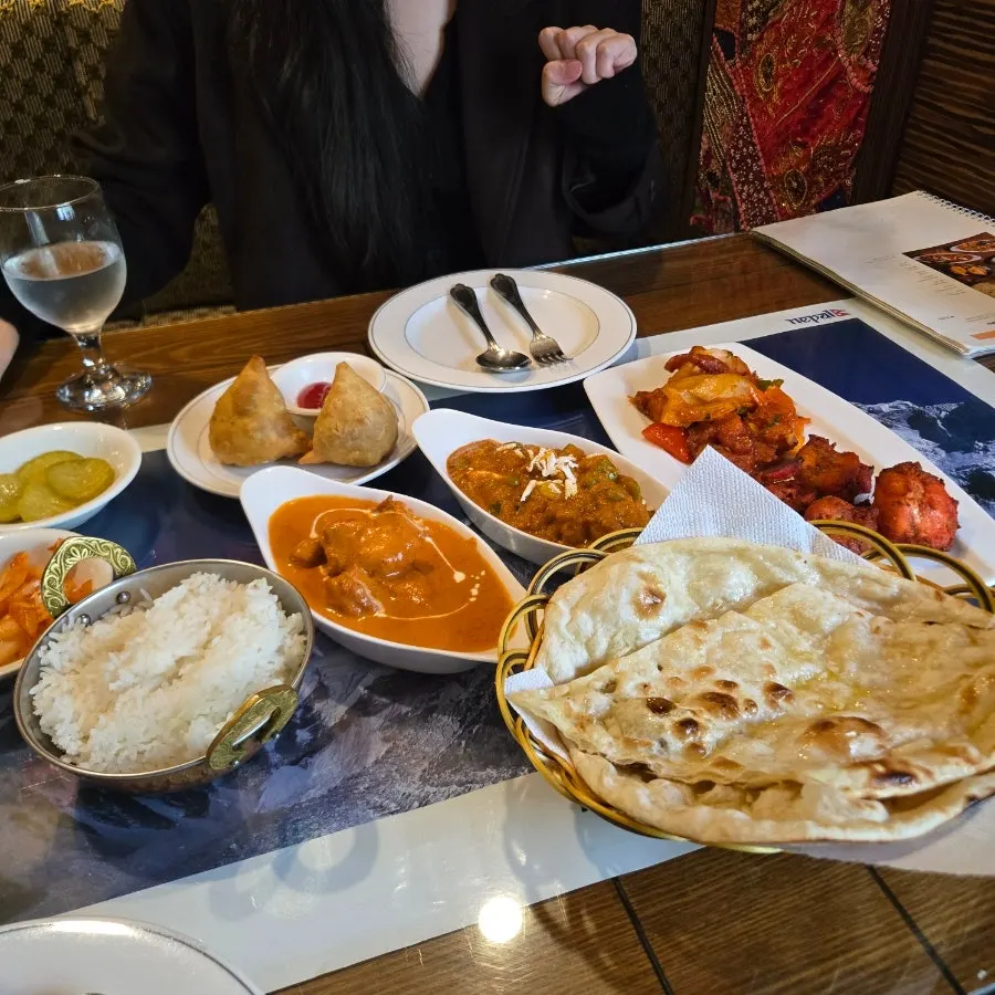 Table filled with curry, naan, and samosa
