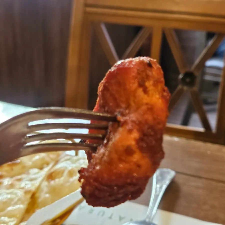 A piece of chicken tikka picked up with a fork
