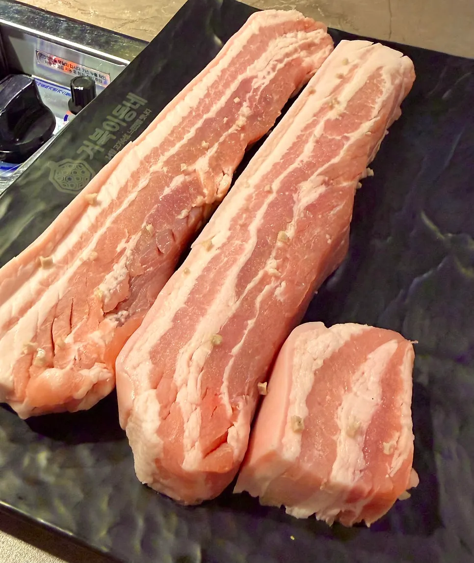 Thick pork belly cooking on the grill