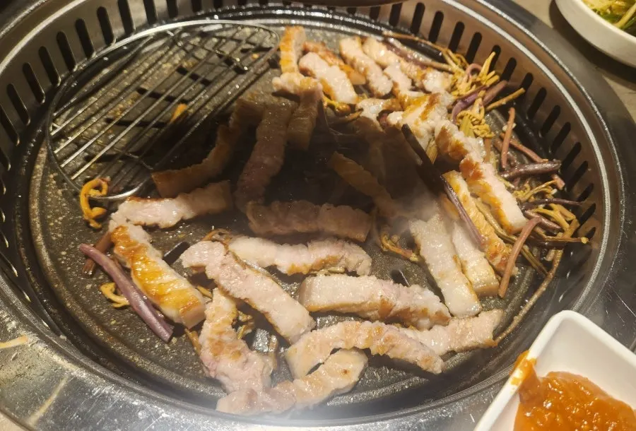Pork belly grilling alongside bracken