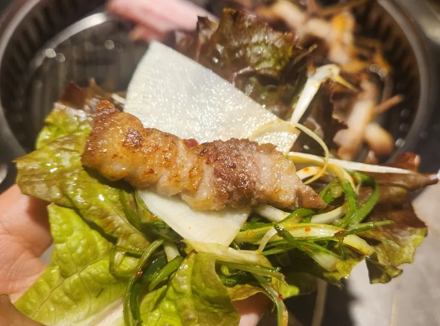 A piece of pork belly on a lettuce wrap