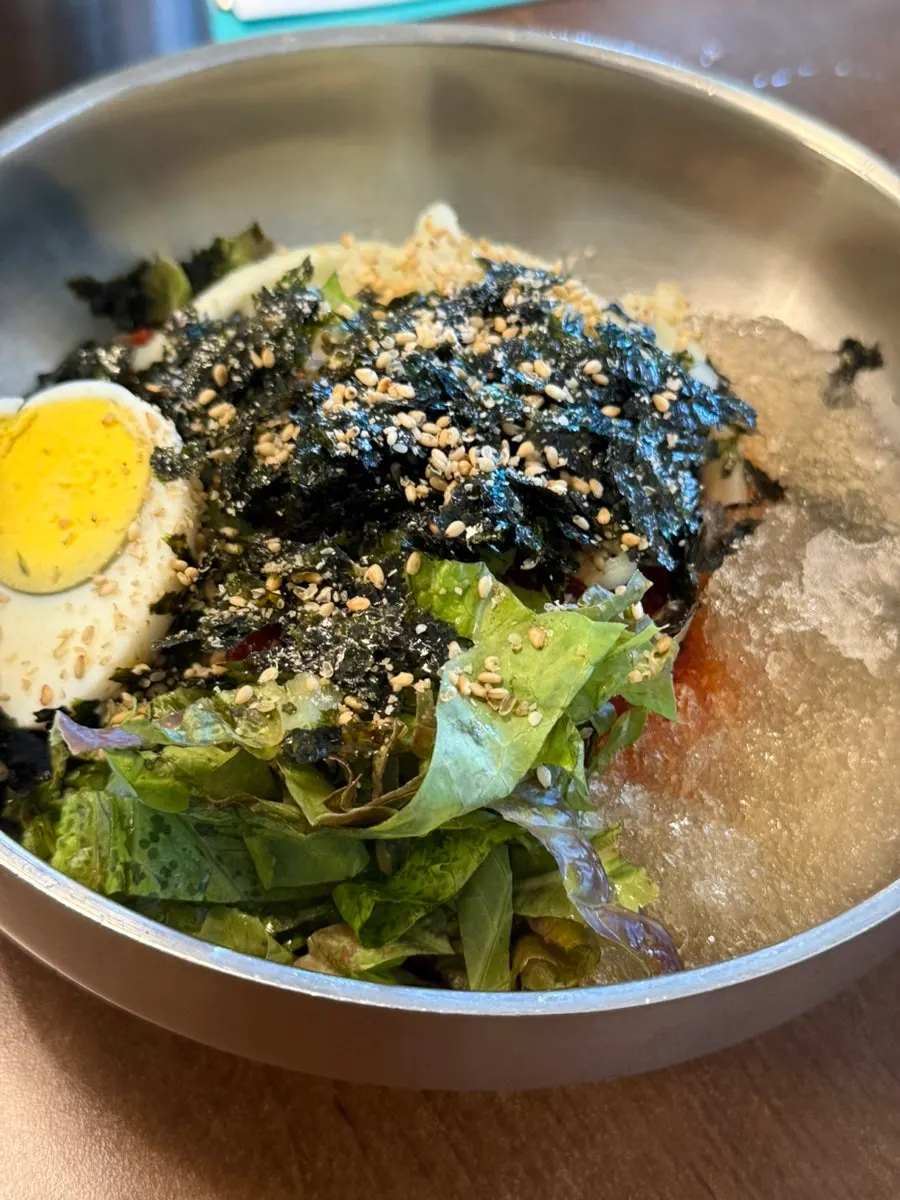Bibim memil makguksu topped with vegetables and seaweed flakes