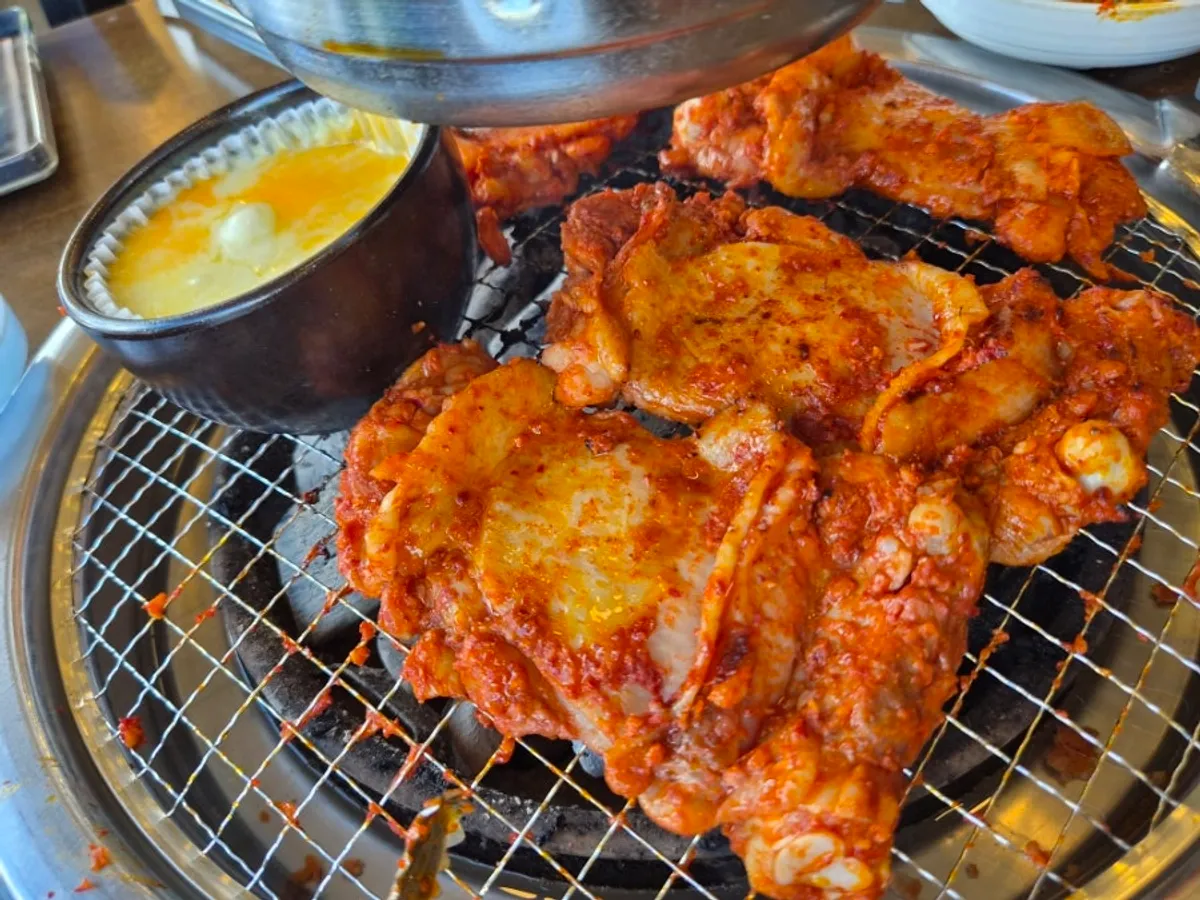 Hand-marinated grilled dakgalbi cooking over charcoal