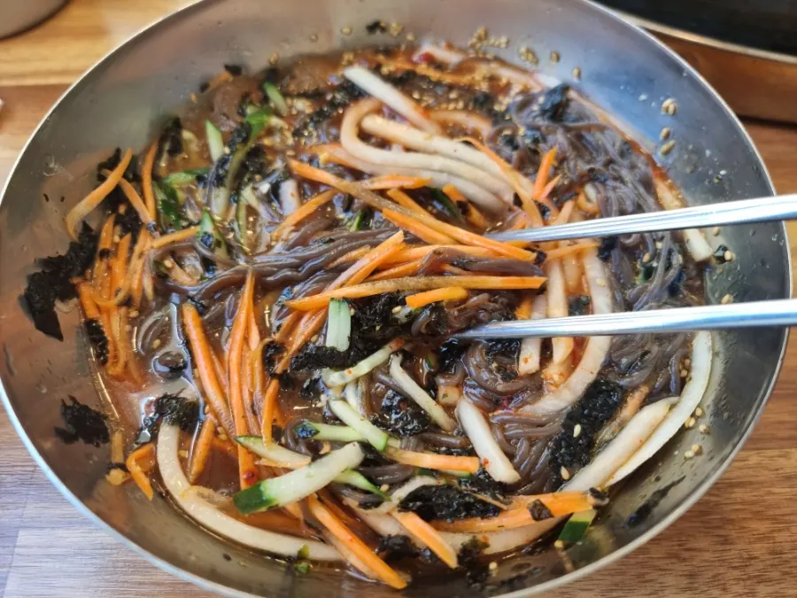 Memil-guksu topped with cucumber and carrot garnish