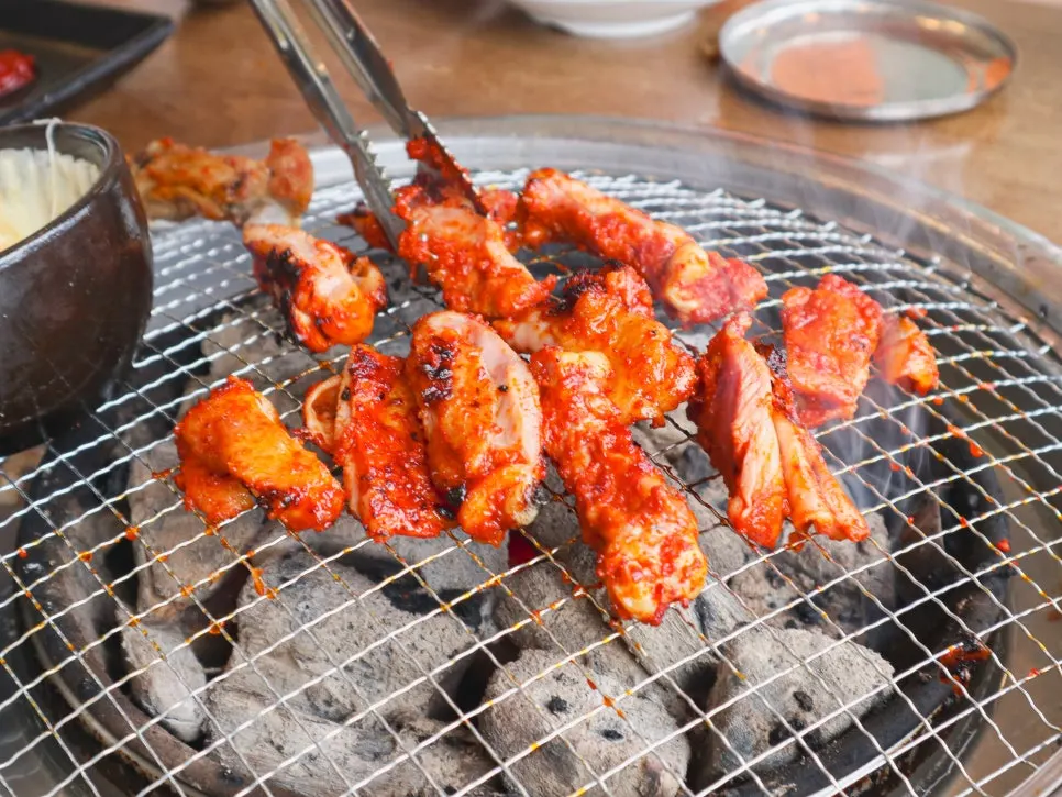 House-marinated dakgalbi placed on the charcoal grill