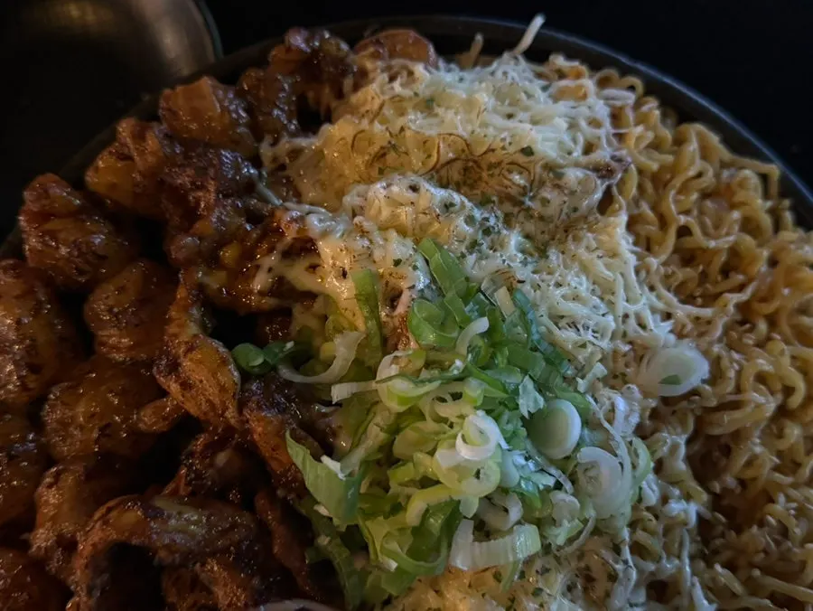 A chopstick-full of ramen noodles with stretching cheese