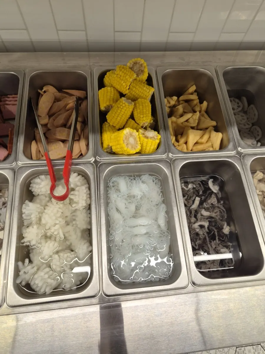 Hotpot ingredients including corn, silky konjac noodles, and potatoes