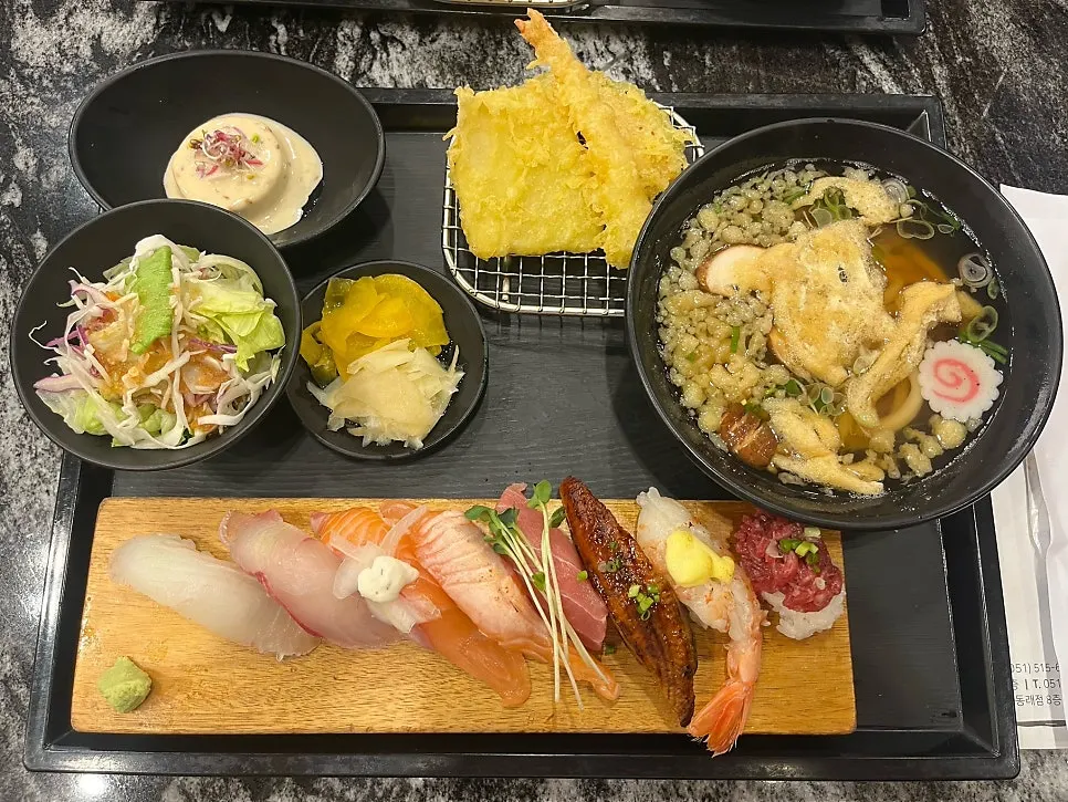 Table set with udon, tempura, and salads