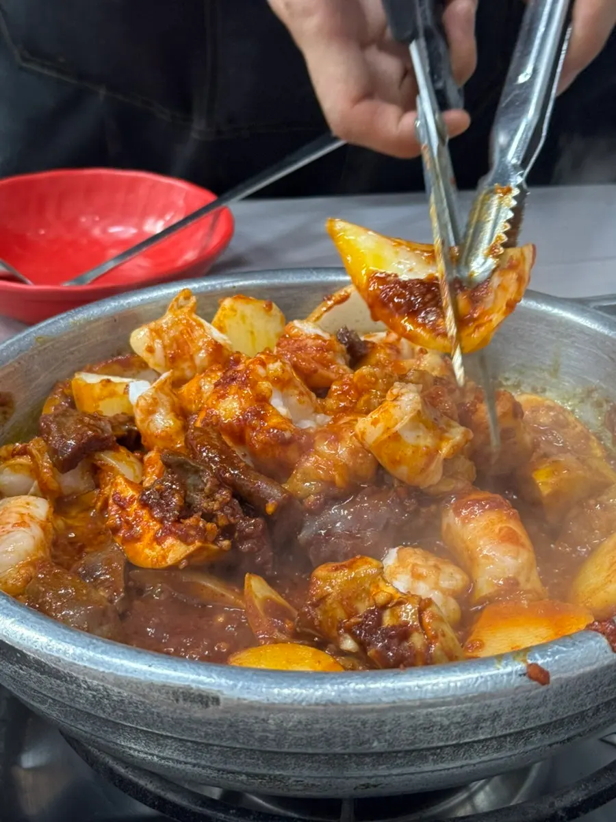 Sauce-covered yang gopchang cooking on the stone pan