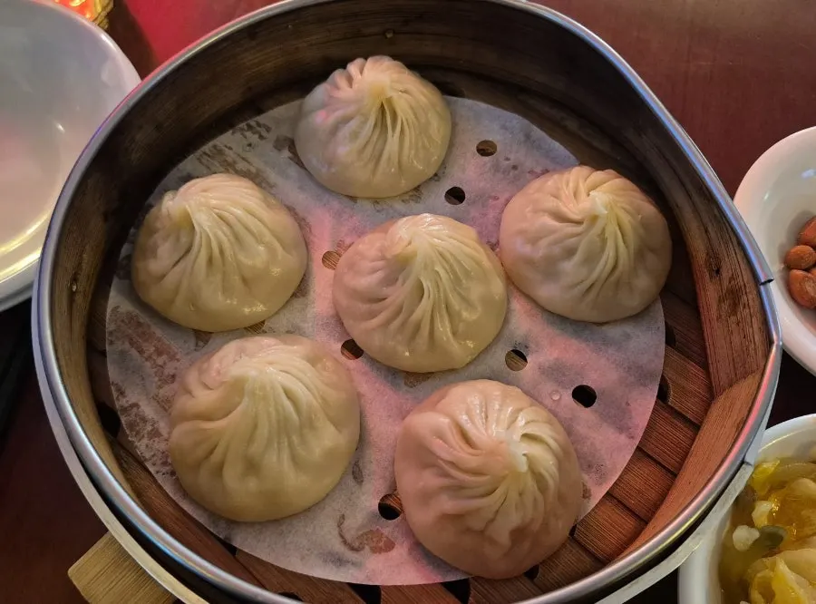 Five pieces of xiaolongbao served in a bamboo steamer