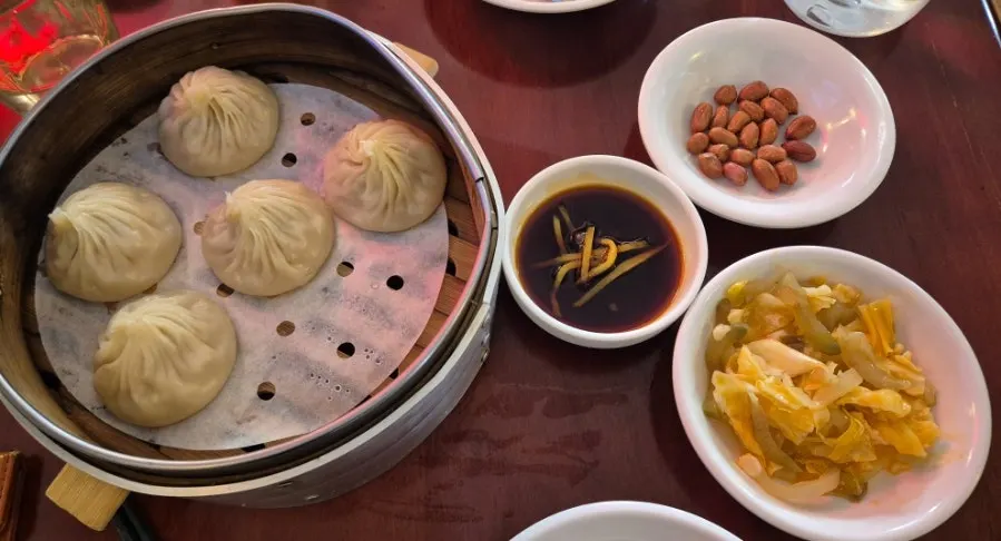 Xiaolongbao lifted onto a spoon with shredded ginger
