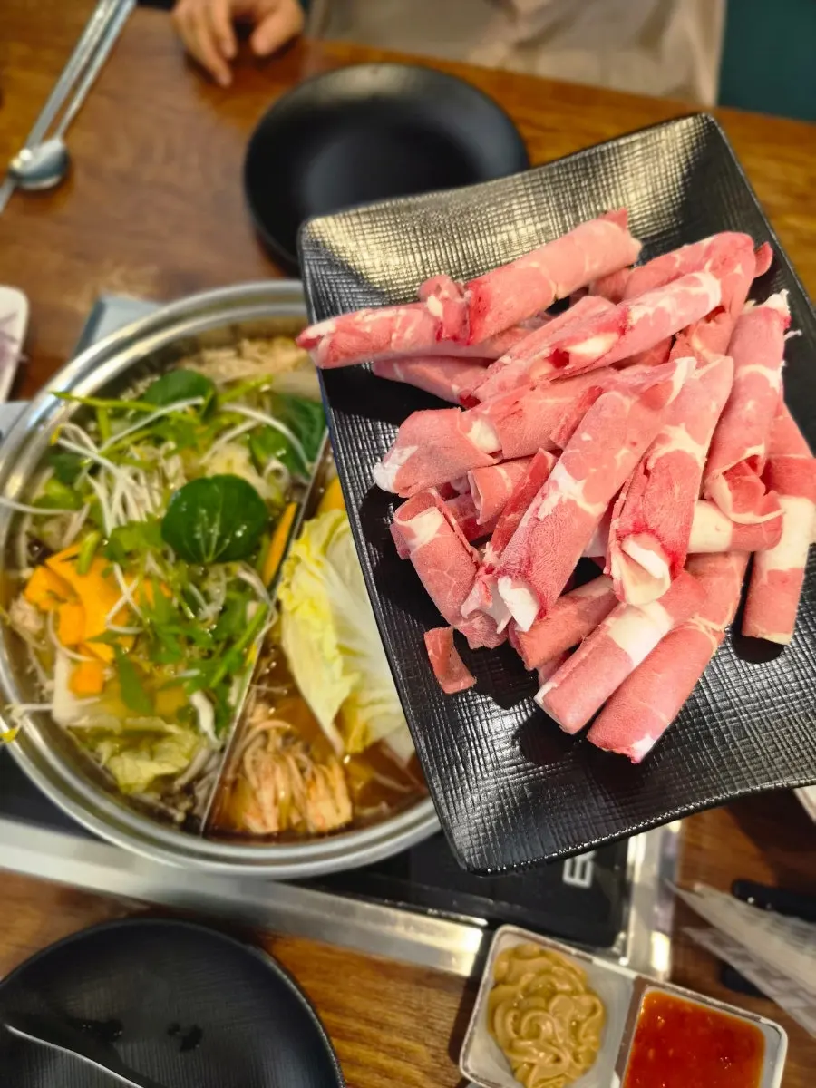 Table filled with shabu-shabu and Vietnamese wraps