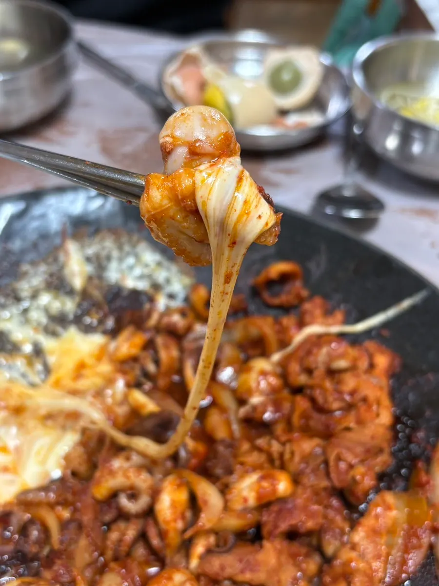 A piece of jjuksam wrapped with melted cheese