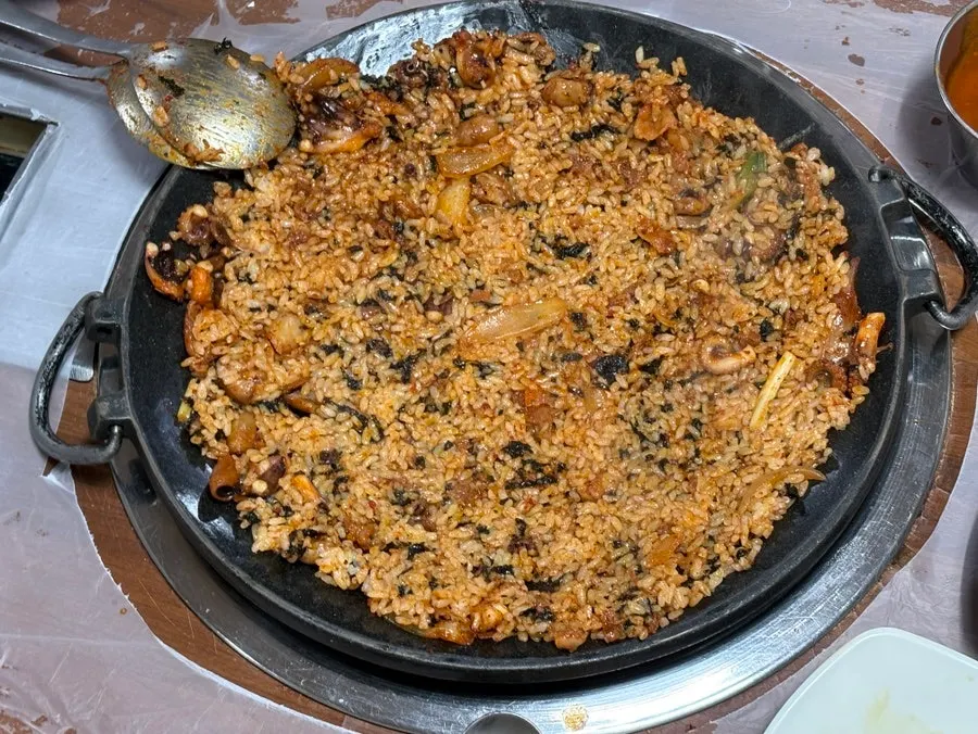 Fried rice being mixed with chopped octopus