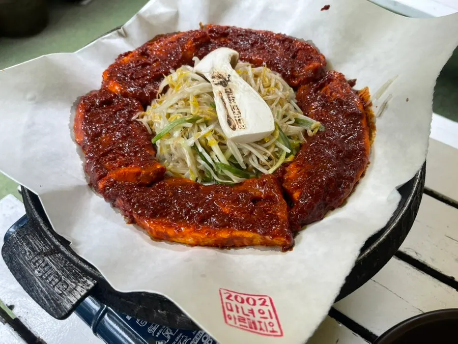 Table spread of tomato-jang pork belly with brand stamped into the meat