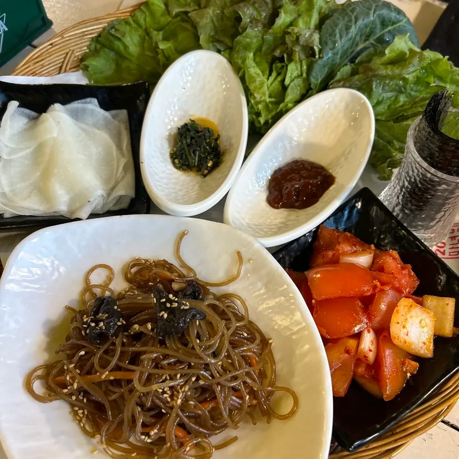 Basic side dishes: lettuce, radish wraps, tomato salad, and japchae