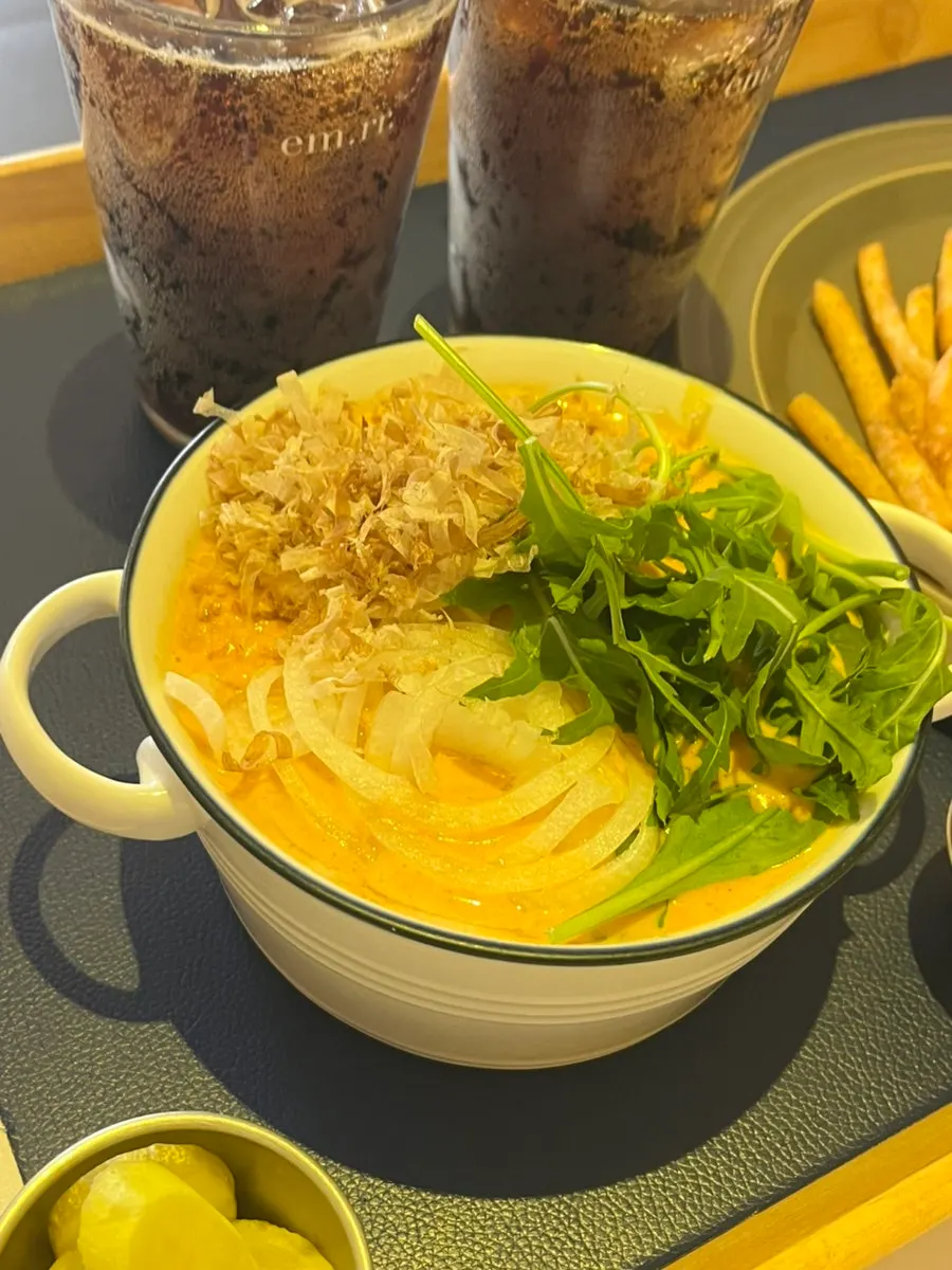 Spicy cream curry udon topped with onion and arugula