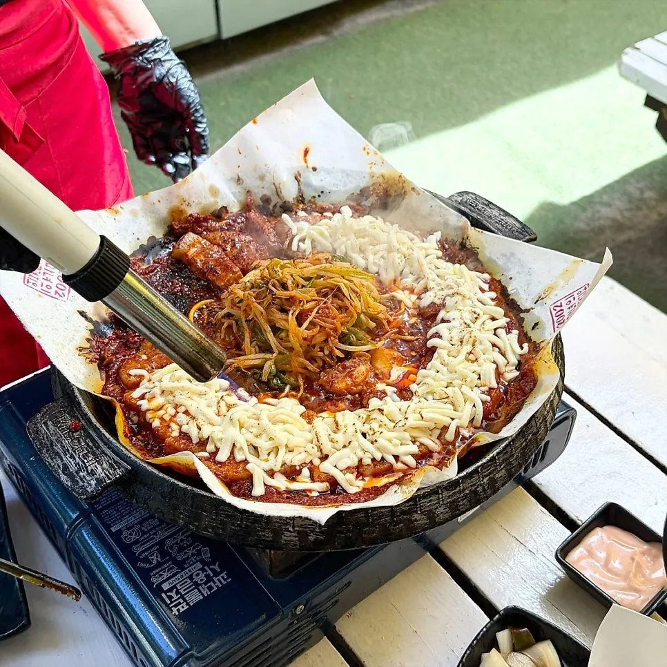 Tomato-marinated pork belly being grilled by a staff member