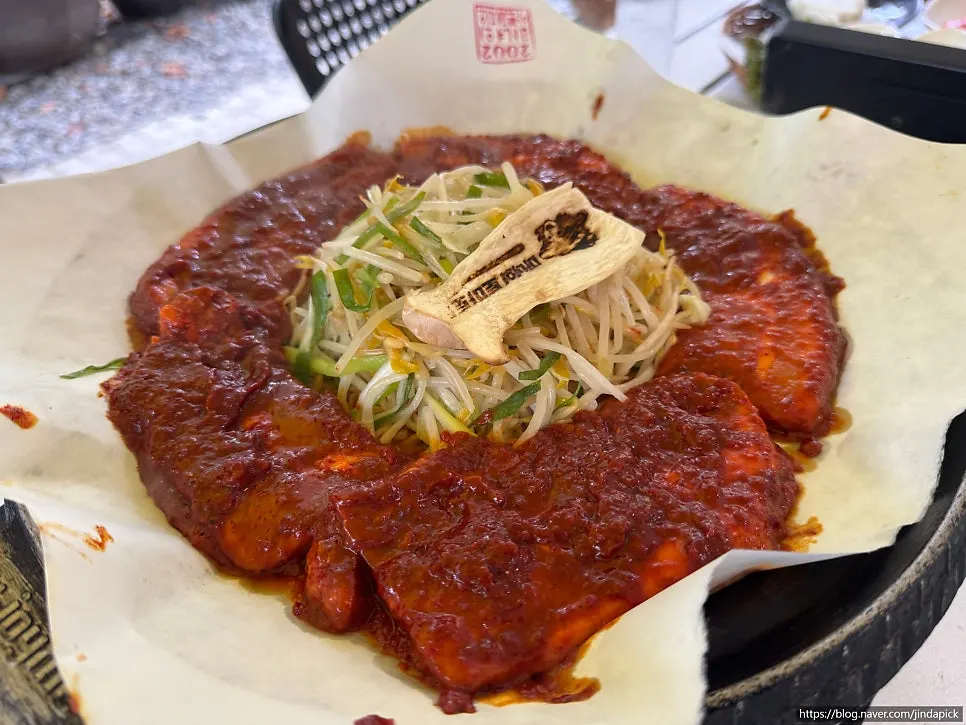 Plate of pork belly coated in red tomato-jang sauce