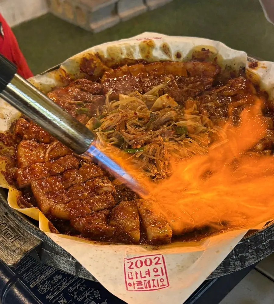 Torch searing smoky flavor into the tomato-jang pork belly