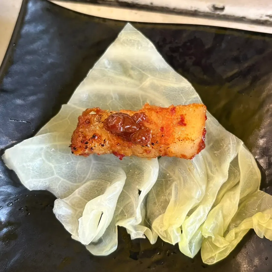 A piece of pork belly coated in spicy sauce