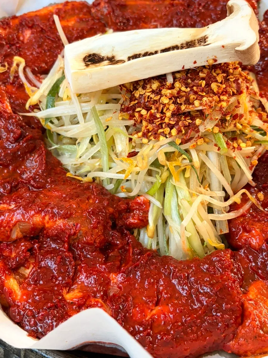 Four servings of tomato-jang pork belly topped with scallions, bean sprouts, and mushrooms