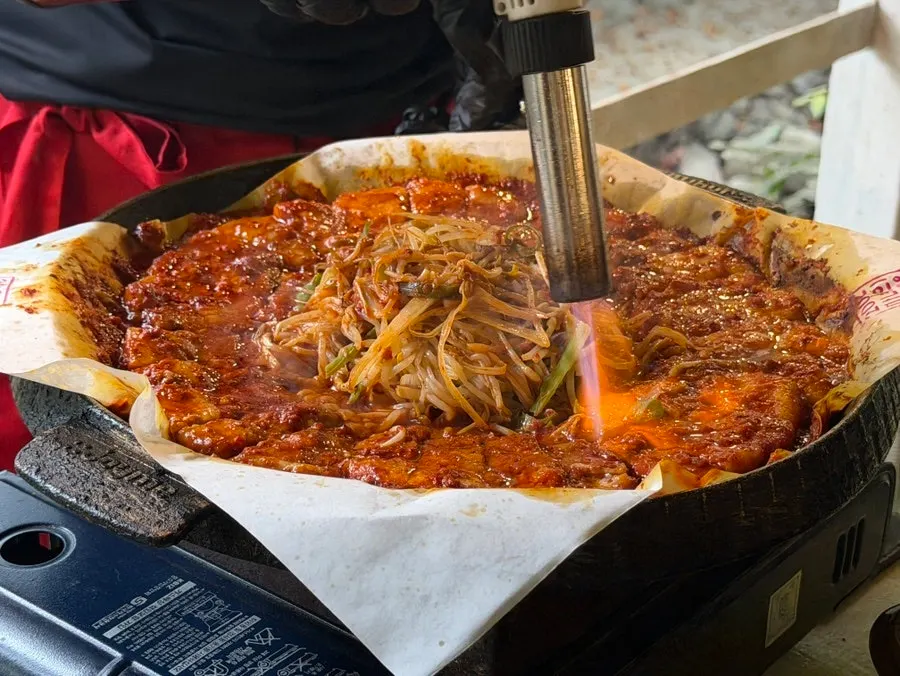 Staff member torch-finishing the tomato-jang pork belly