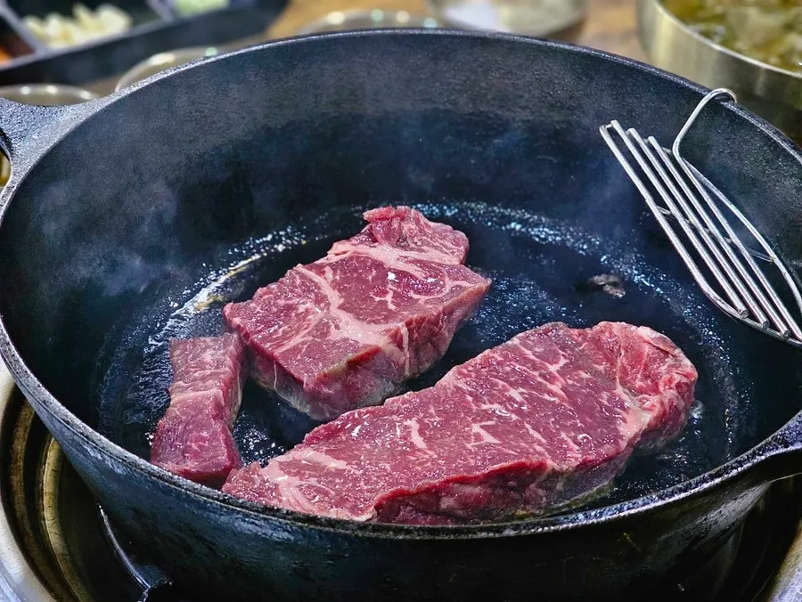 Thick-cut sirloin placed on an oiled iron pan