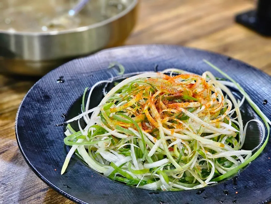 Napa cabbage doenjang soup and scallion salad served alongside