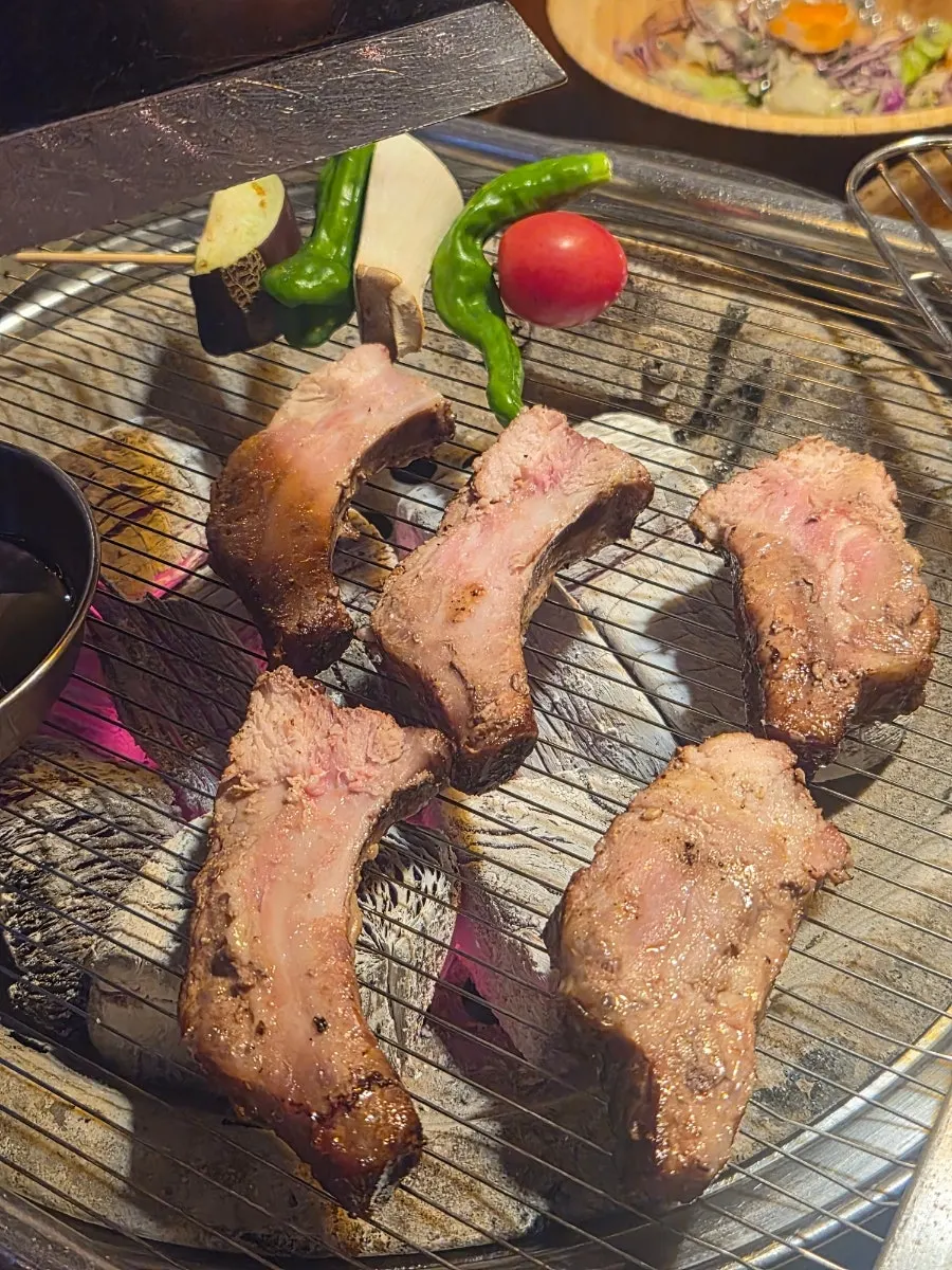 Thick pork back ribs grilling over real charcoal