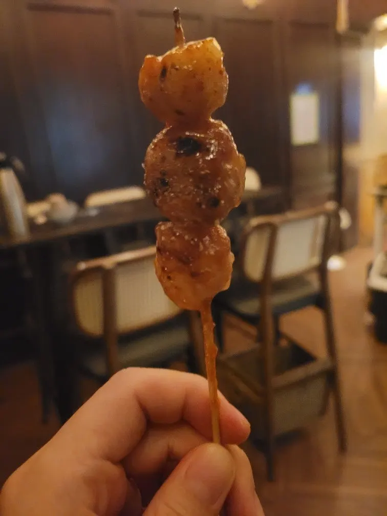 A beef intestine skewer held up by hand