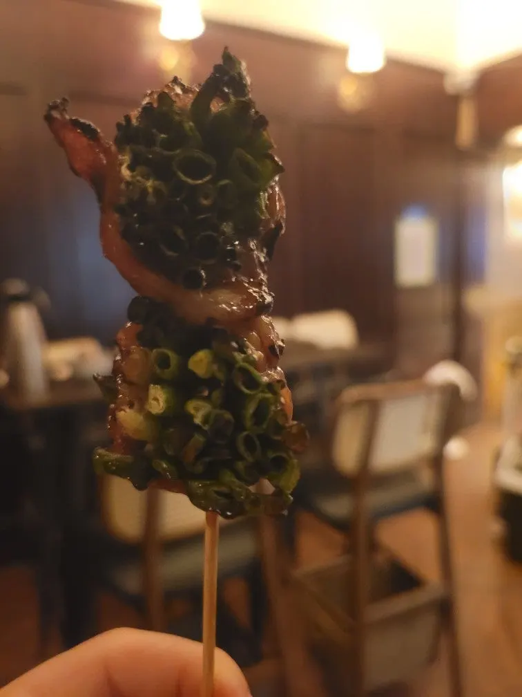 Close-up of an upright pork belly and scallion skewer cross-section