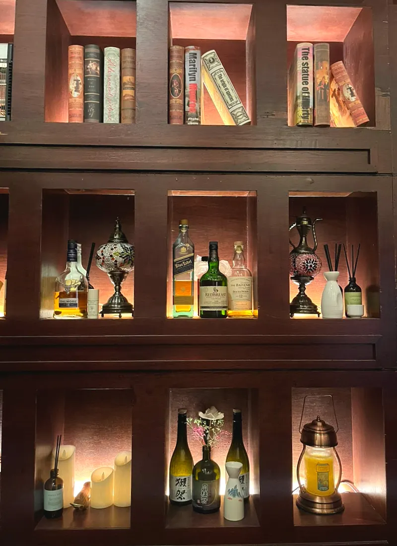 Wall interior of Nani Byeolgwan decorated with books, liquor bottles, and candles