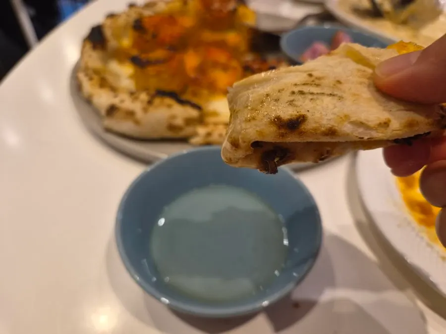Wood-fired pizza crust dipped in self-serve honey