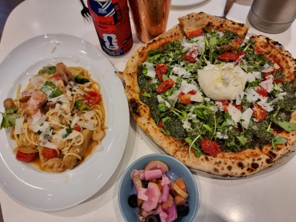 Table with burrata pizza and gamberi oil pasta