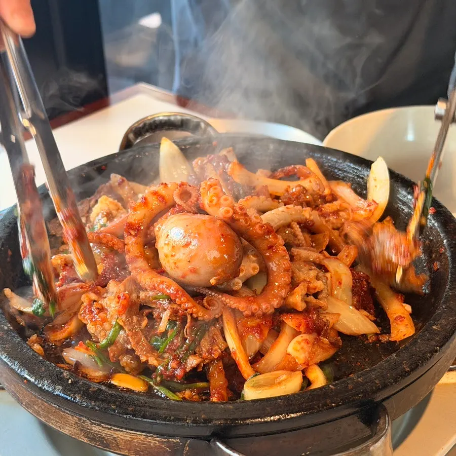 Live octopus and beef cooking on the stone plate