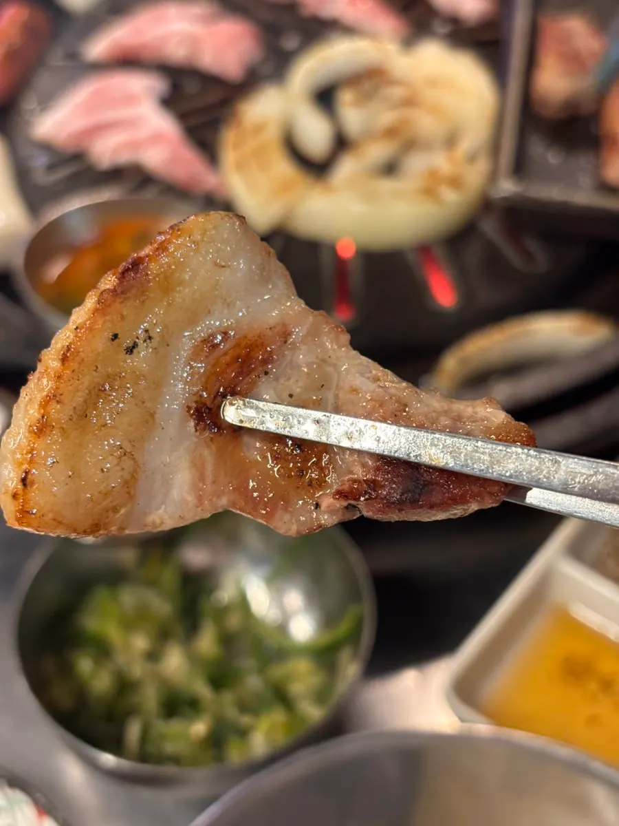 A piece of meat topped with pickled scallions and chili