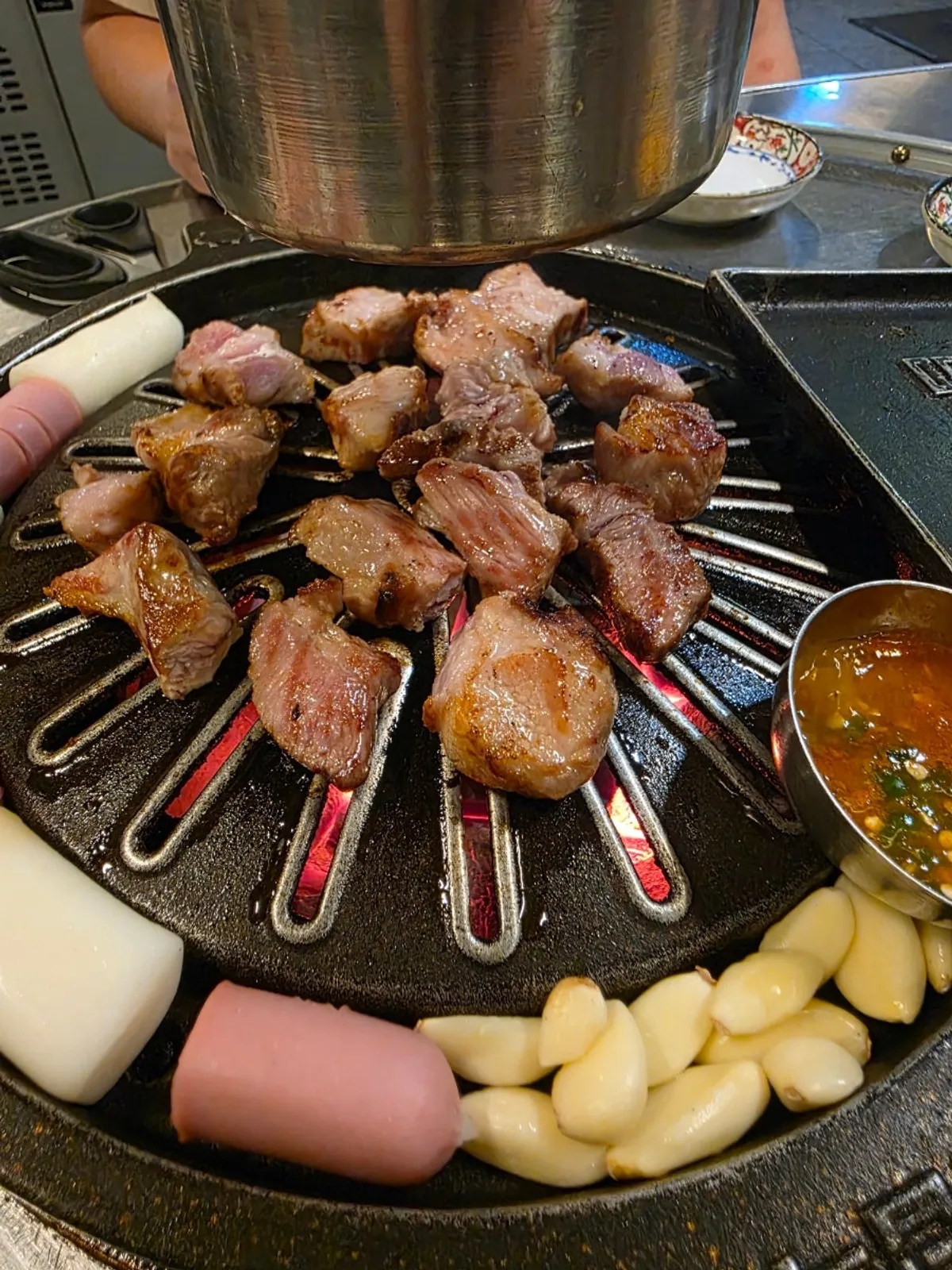 Mixed grill cooking on the cast-iron griddle at Neopttakjip Samsong Branch