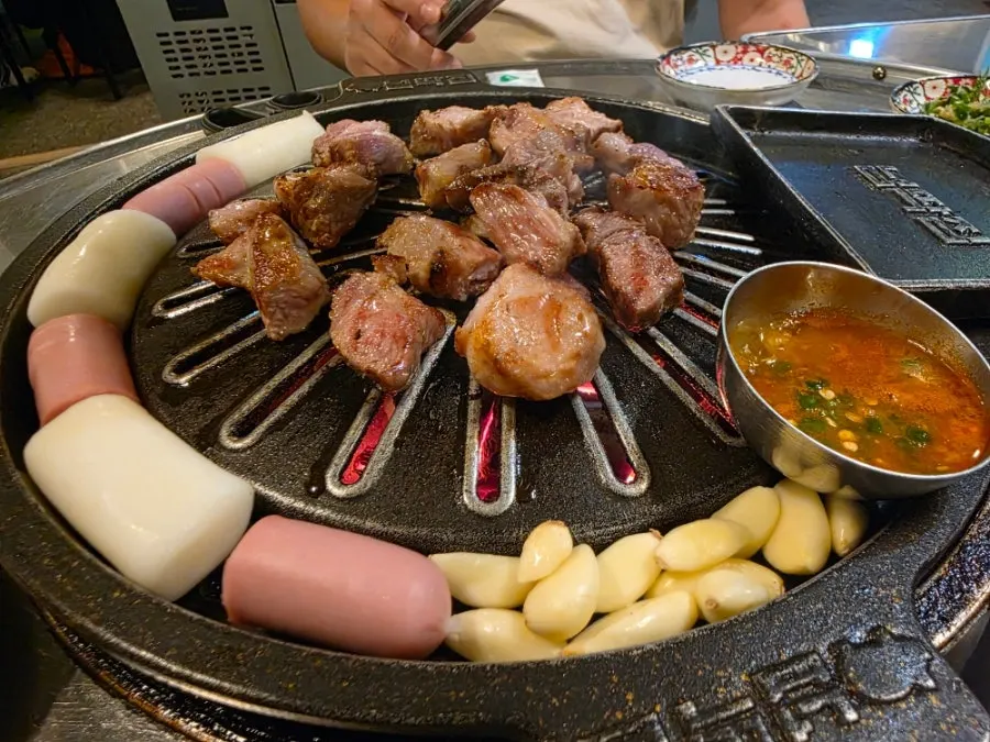 Meat and garlic cooking on the specially made cast-iron griddle
