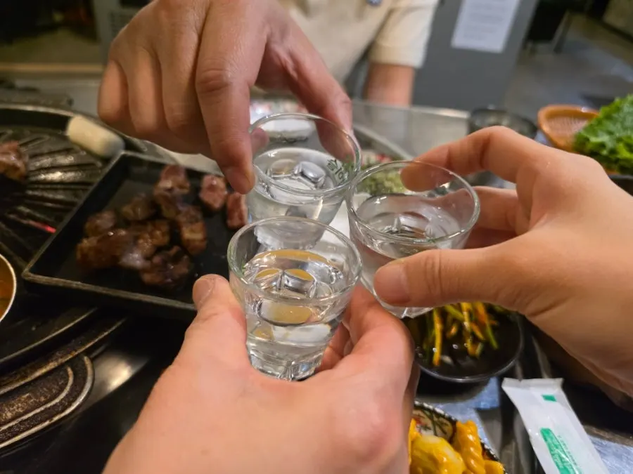 Soju glasses set beside the grilled meat