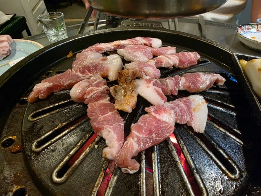 Garlic, rice cake, and sausage grilling at the edge of the griddle