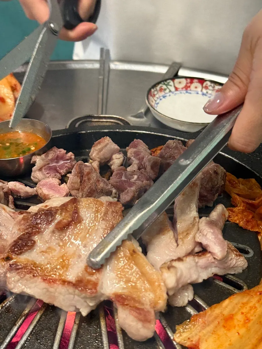 Bone-in raw ribs being cut with scissors on the grill